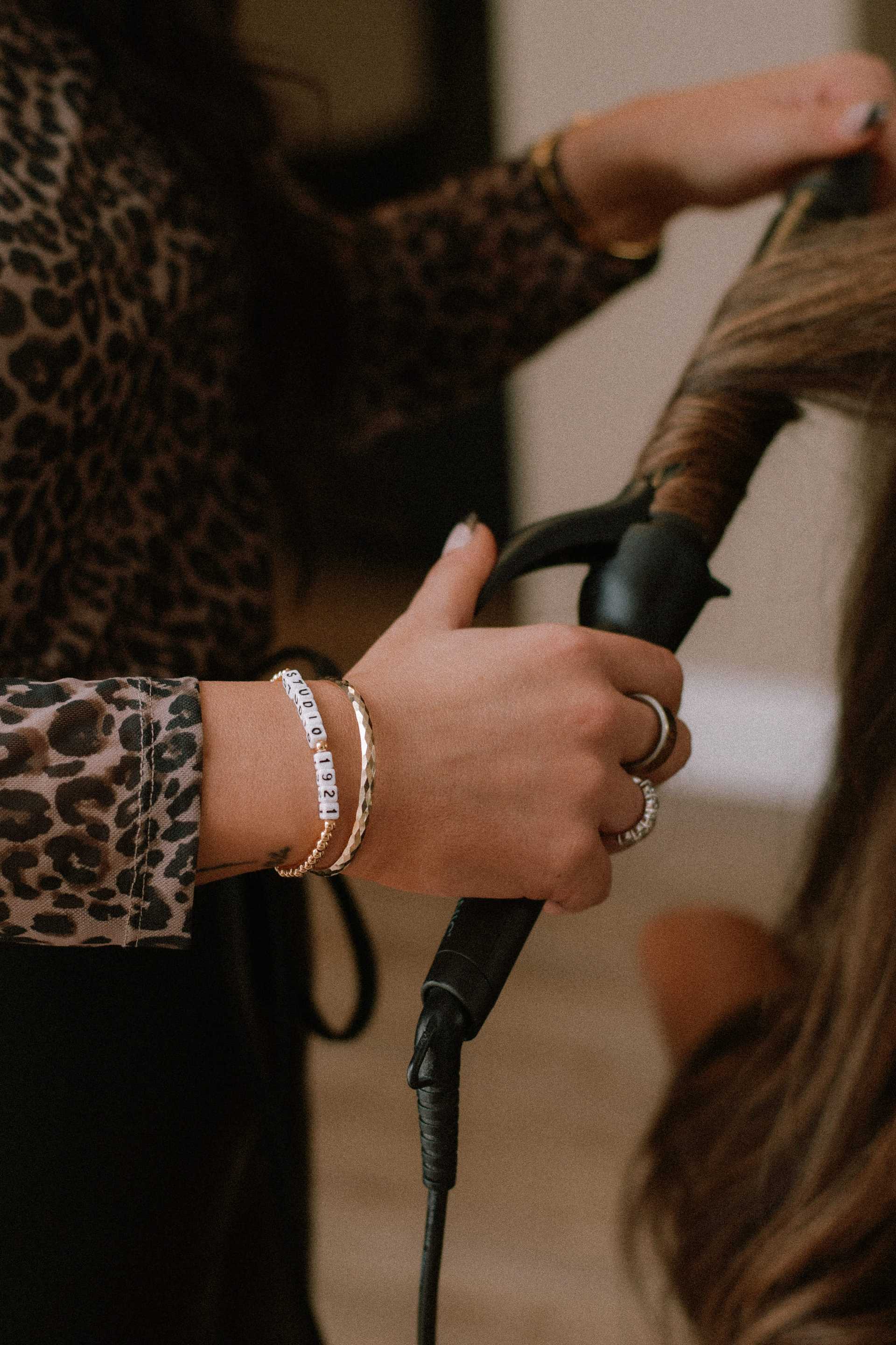 Stylist using a curling iron on a client's hair in a salon setting.