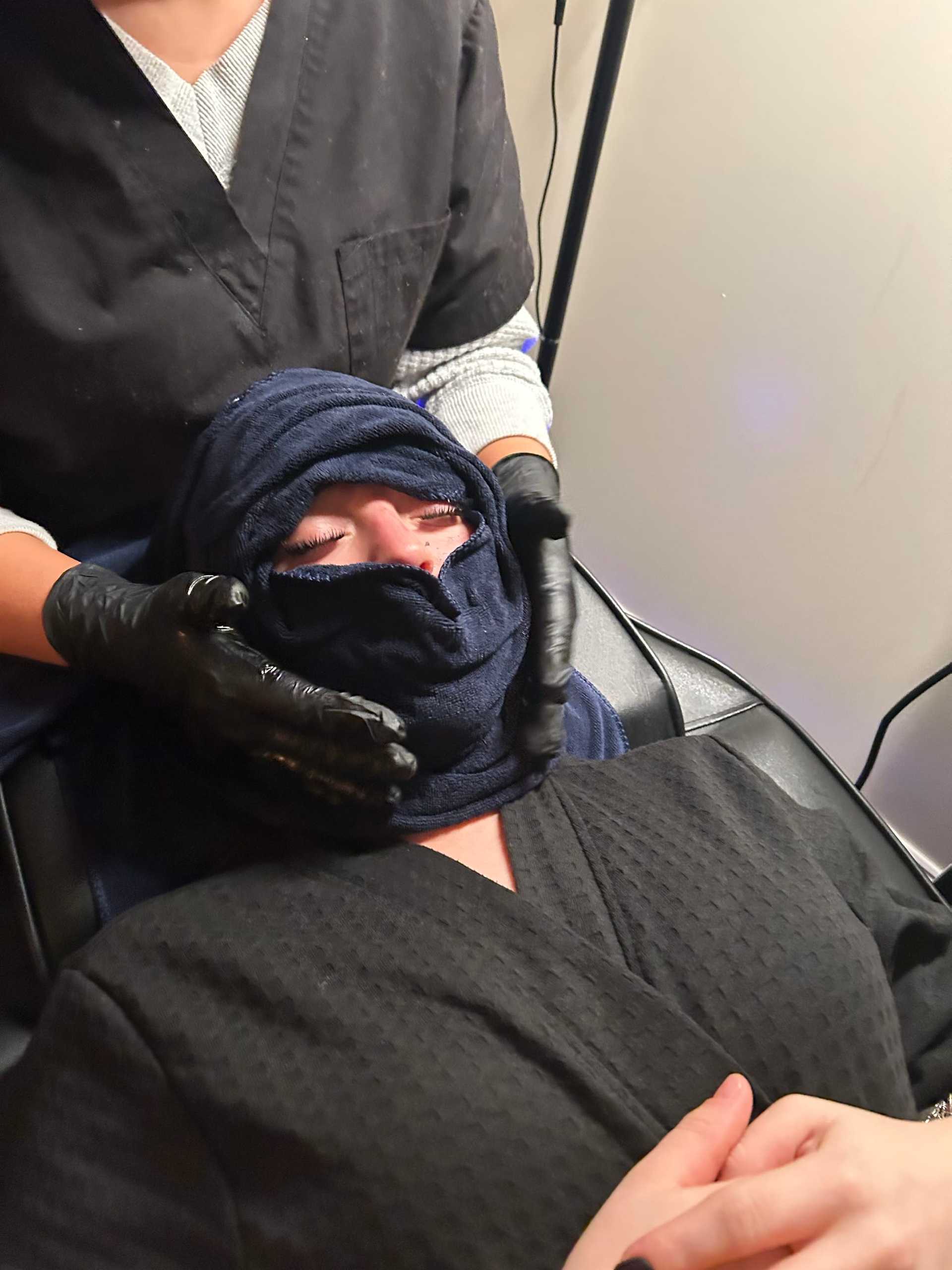 Facial treatment with warm towel wrap at a spa, person relaxed on a chair.